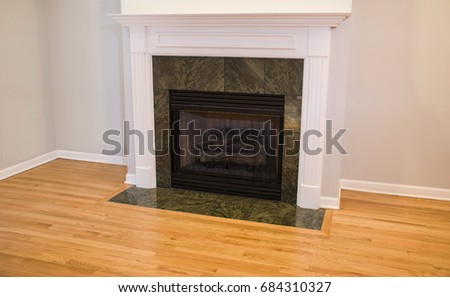 Fireplace with green granite around, hardwood floor and white crown molding, no fire