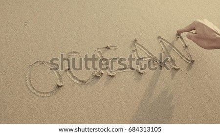 OCEAN written on the beach sand washed aways by waves.