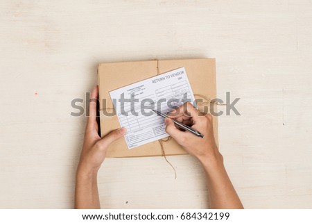 Top view of deliveryman making notes in "return to vendor" delivery receipt at table Royalty-Free Stock Photo #684342199