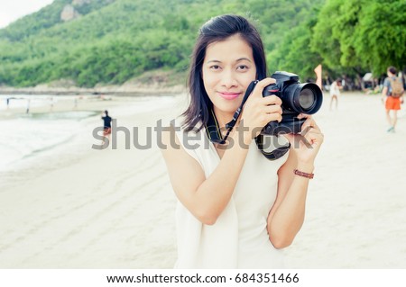 Asian women taking photos, on the beach.