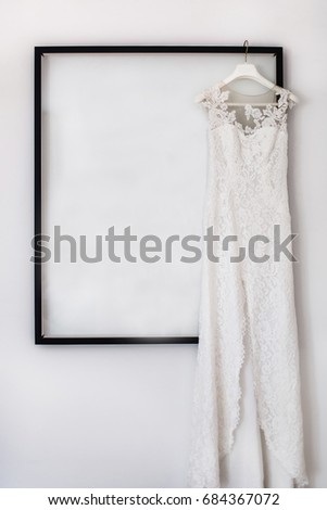 Wedding dress hanging on the picture in the white room.