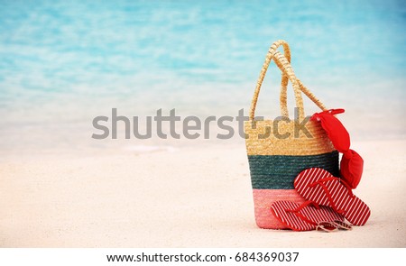 Bag with flip-flops and swimming suit on sea beach. Summer vacation concept