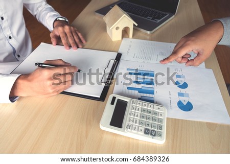 Man sign a home insurance policy on home loans, Agent holds loan investment chart graph documents, pointing and calculating table installment payment, Real Estate concept.