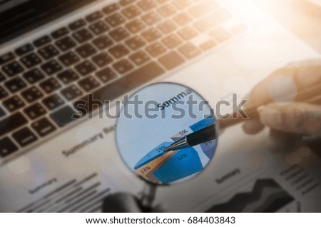 Businessman checking a graph with a magnifying glass, closeup