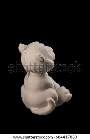 White plaster statuette figurine toy tiger on a black background