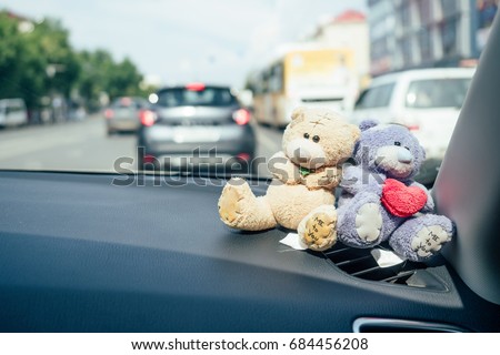 Teddy bears stand in the car. Against the background of other cars on the street. Valentine's Day