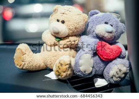 Teddy bears stand in the car. Against the background of other cars on the street. Valentine's Day