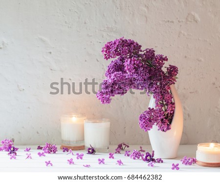 flowers in vase with candles on background white wall