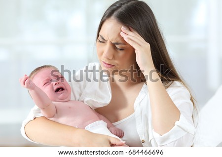 Desperate mother holding her angry baby crying  Royalty-Free Stock Photo #684466696