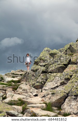 the boy in the mountains in the background of a stormy sky