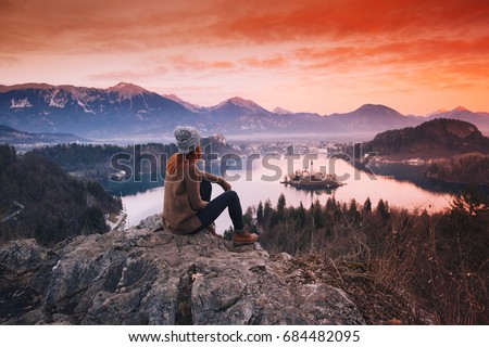 Travel Slovenia, Europe. Woman looking on Bled Lake with Island, Castle and Alps Mountain on background. Top view. Bled Lake one of most amazing tourist attractions. Sunset winter nature landscape. Royalty-Free Stock Photo #684482095