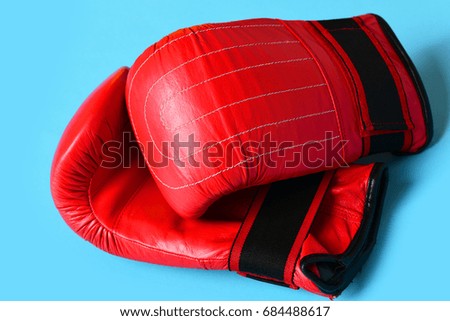 Pair of leather boxing sportswear. Sport equipment isolated on cyan blue background. Boxing gloves in red color. Professional box and strong fight concept