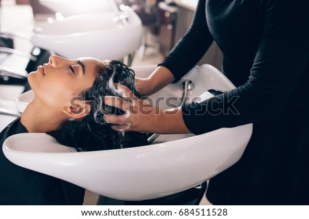 Woman applying shampoo and massaging hair of a customer. Woman having her hair washed in a hairdressing salon. Royalty-Free Stock Photo #684511528
