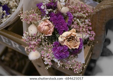 dried flowers bouquet in a basket on display at flower shop. Sweet and romantic concept. Selective focus on the pink rose.