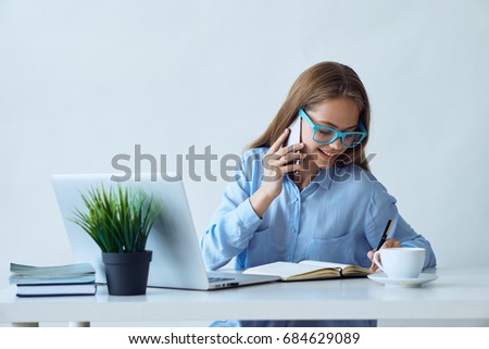 Young beautiful woman working at computer in office and calling by phone.