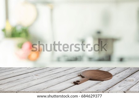Blurred and abstract kitchen background. Empty wooden tabletop with cutting board  and defocused modern kitchen for display or montage your products.
