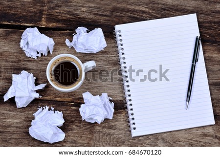 Notepad with pen coffee and crumpled paper on desk close-up