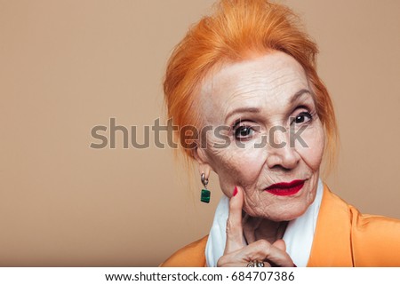 Picture of amazing mature redhead fashion woman standing isolated at studio and posing. Looking at camera.