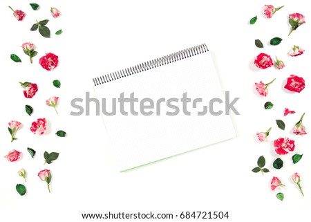 Open spiral notebook and rose flowers frame. Flat lay, top view