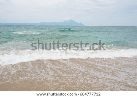 waves on beach with mountain in background