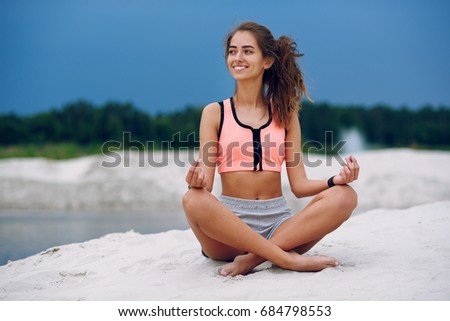 Healthy energy woman balance body and practicing yoga and meditate on the beach in the sand on the background of blue cloudy sky. Healthy Concept. Close up portrait.