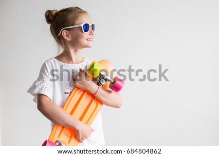 Stylish little girl child with skateboard over white background