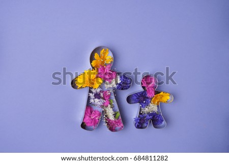 Two iron figurines of dad and child on the blue flat with a lot of flowers . The mix of flowers on the blue flat. 