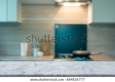 Blurred and abstract kitchen background. Empty marble tabletop and defocused modern kitchen for display or montage your products.