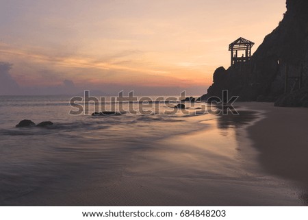 Beautiful scenery at the beach with silhouetted wooden hut during sunrise.