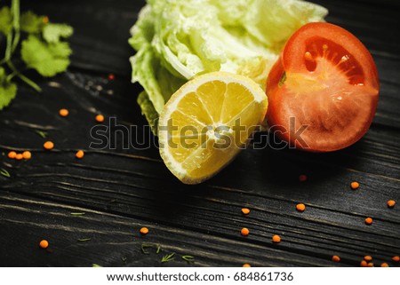 black wooden background. Blackboard. Grunge texture. Green and groats and tomato with yellow slice lemon. Copy space for text and design. Top view wood with Food. Vegetables for vegeterian.