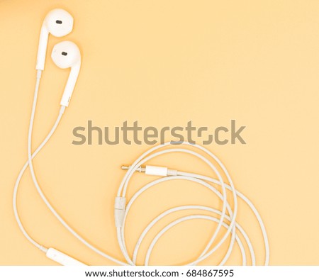 Top view of White Earphones on Orange background. Copy space. Music is my life concept