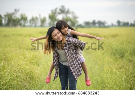 Happy family in mother's day concept,I Love you mom.Asian mother and little cute daughter playing together in park (rice field).Mother and adorable little girl greeting and hug together.