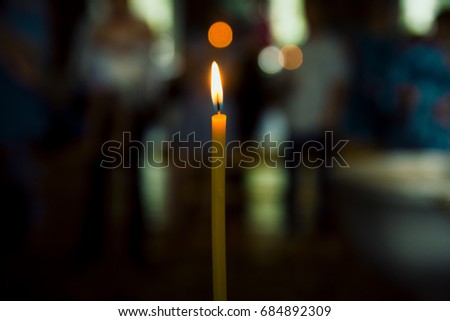 Photo of a burning church candle on a blurred background