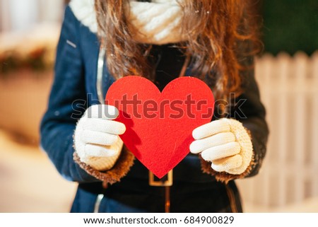 Girl holding heart on Valentine's day in winter outdoors