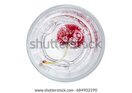Close up the red ripe cherry in soda water with bubbles of carbon dioxide on white background.