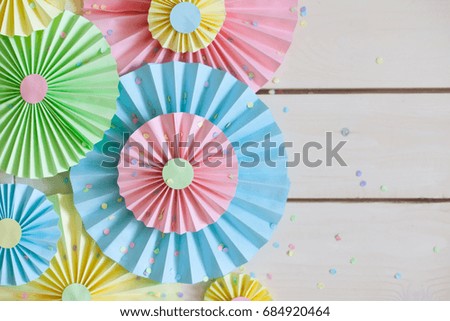 Colorful bright pastel paper rosette. Decorating for a party. White wood background