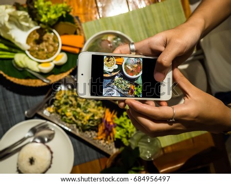 Happiness Thai Local Meal Enjoying Dinning Eating Concept. Happy Time at a Dinner. Top view of people shooting dinner on mobile phone while sitting at the wooden table.