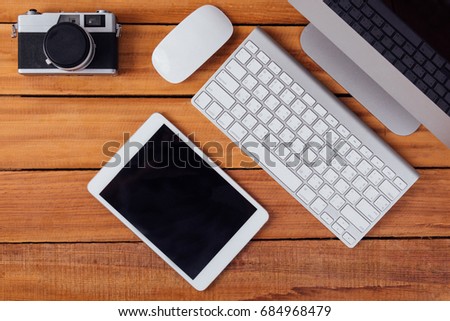 Creative flat lay photo of workplace desk with retro camera and  tablet on wood table