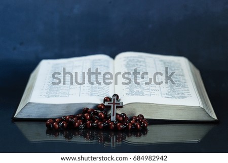 Bible and a crucifix on a glass table. Beautiful dark background.Religion concept.