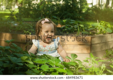 Happy little girl playing in summer garden in sunny day, toned photo