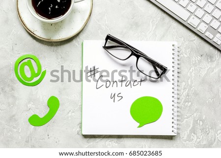 customer support service desktop with contact us signs on gray background top view