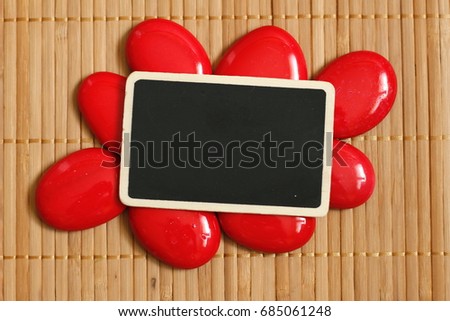An empty slate to write a message surrounded by red pebble and bamboo floor