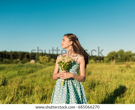 Beautiful teenage girl in blue dress dance to camera on the summer field, Sun Light. freedom concept