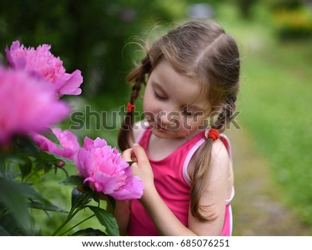 A beautiful and peaceful photo of a little girl smelling big bright flowers with her eyes closed