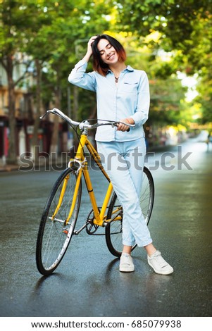 Lovely woman with a yellow bicycle on the road