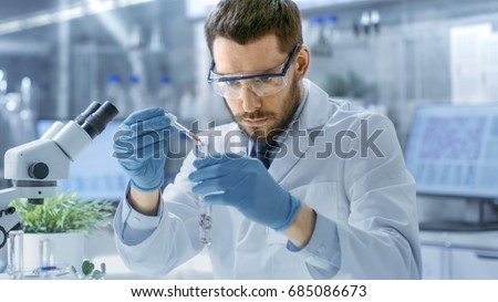 In a Modern Laboratory Biologist Conducts Experiments by Synthesising Compounds with use of Dropper and Plant in a Test Tube. Royalty-Free Stock Photo #685086673