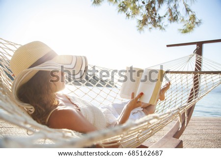 Woman in a hammock with book on summer day Royalty-Free Stock Photo #685162687