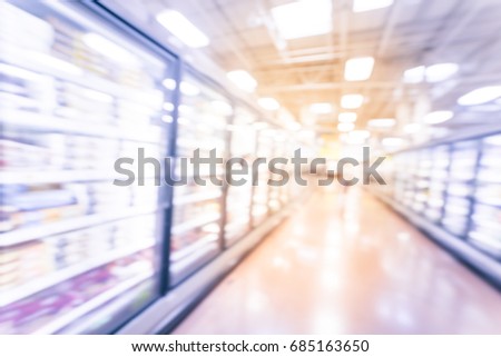 Blur frozen food section at retail store in America. Huge glass door aisle with variety pack of processed fruit, vegetable, breakfast, appetizer, side, meals, pizza. Food in supermarket. Vintage tone.