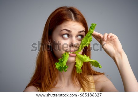 Woman eating salad leaves on a gray background diet, healthy eating                               