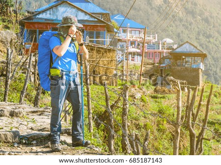 the backpacker is taking a photo on the road trip to Annapurna Base Camp